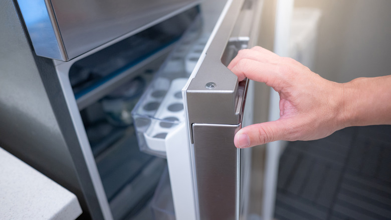 Hand opening the refrigerator door