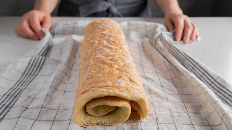 Warm sponge cake rolled up on towel