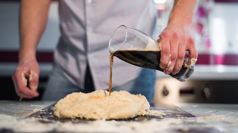 Man pouring beer into dough