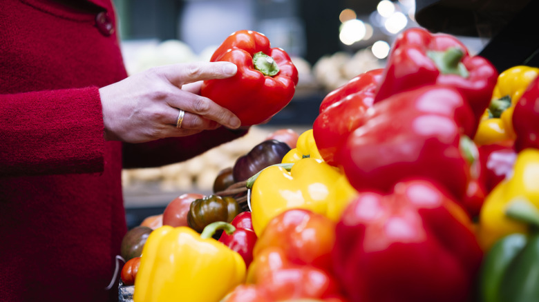 Person holding a red bell pepper in the store