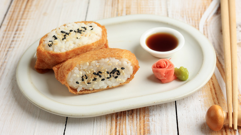 Pieces of inari sushi on plate with dipping sauce