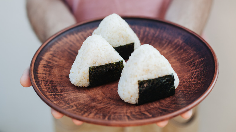 Person holding plate of onigiri sushi