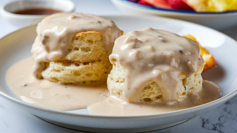 Biscuits and gravy in white bowl on marble countertop