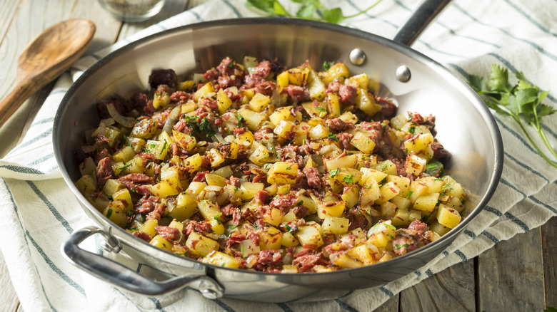 Pan with corned beef potato hash on striped dish towel