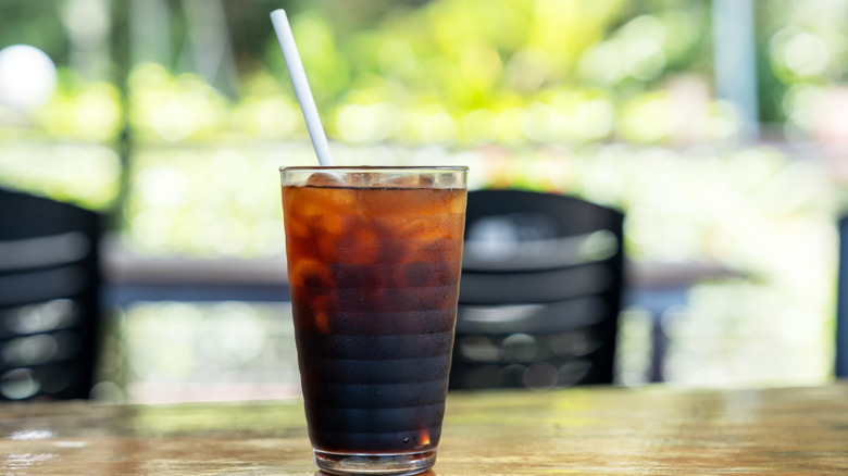 Glass of cold brew coffee with straw on wooden table