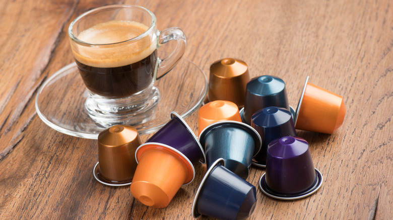 Pile of Nespresso pods next to glass of coffee