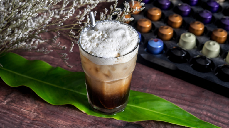 Iced coffee next to variety of Nespresso pods