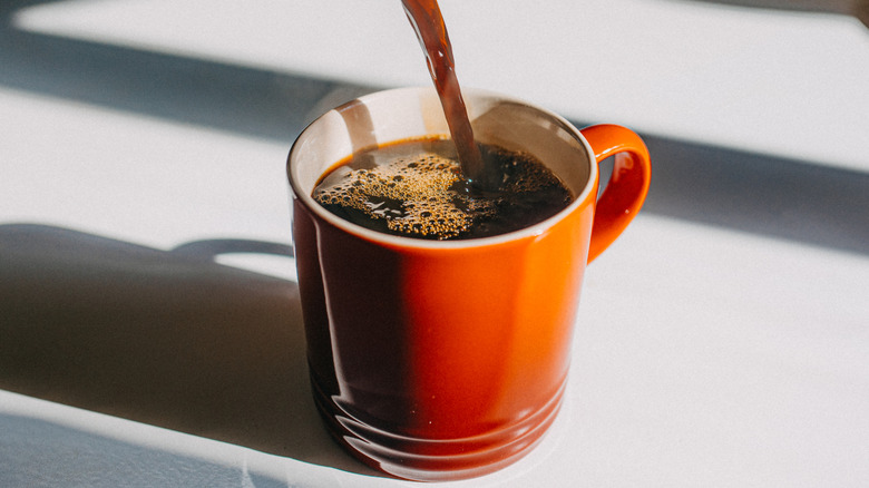 Coffee being poured into orange cup