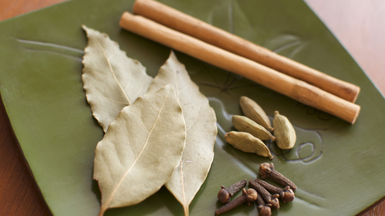 bay leaves, cardamom pods, cloves, and cinnamon on plate