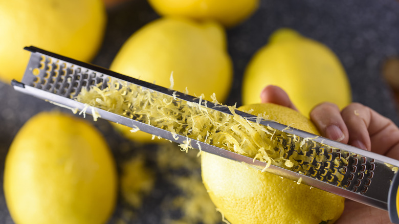 hand zesting a lemon with a microplane