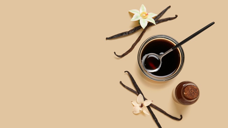 Vanilla extract in bowl surrounded by vanilla pods