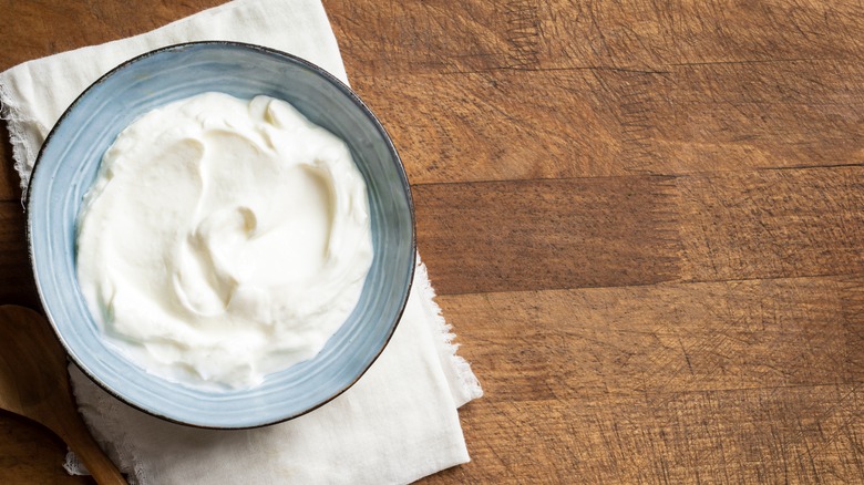 Sour cream in a blue bowl on a wooden table