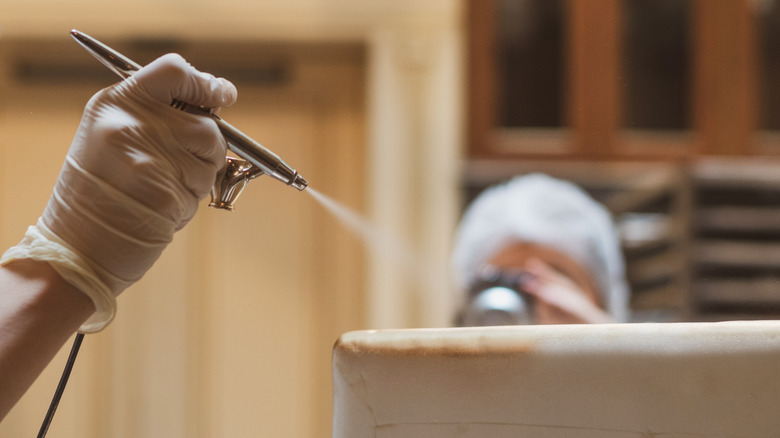 hand of chef airbrushing a cake