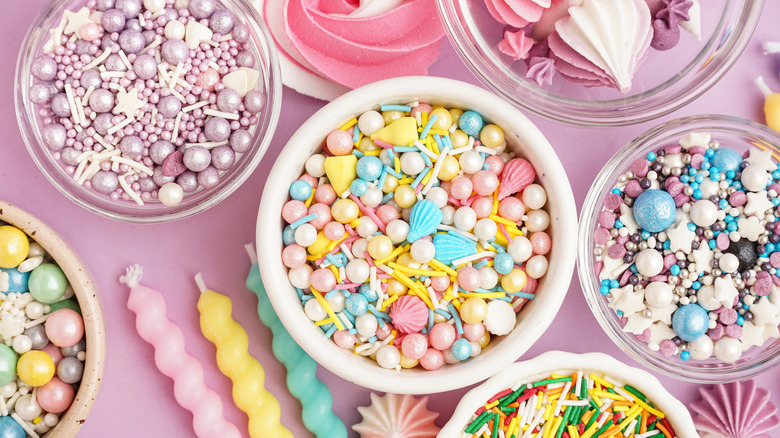 bowls of sprinkles, sugar pearls, and confetti surrounded by meringue cookies