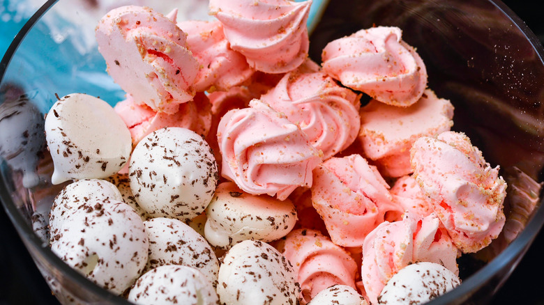 bowl of meringue cookies with toppings like crushed nuts and chocolate