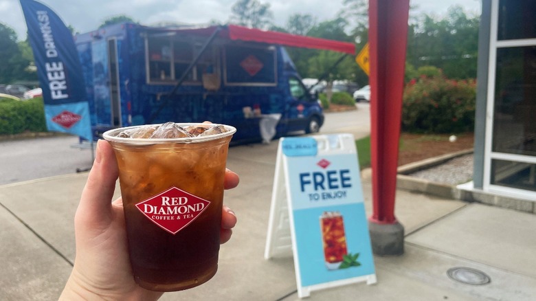 holding iced coffee truck background