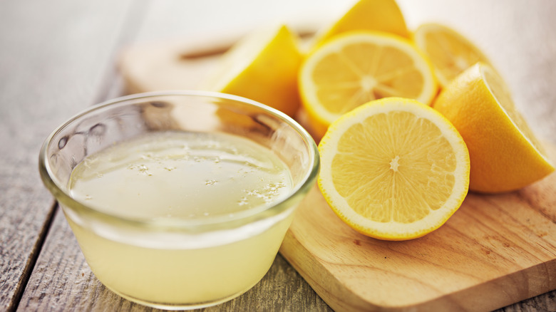 Halved lemons next to bowl of lemon juice