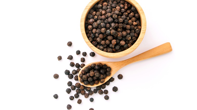 black peppercorns on wooden spoon