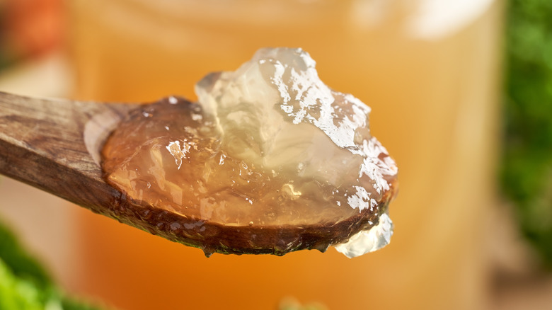 Chilled jellied stock on spoon with jar in background