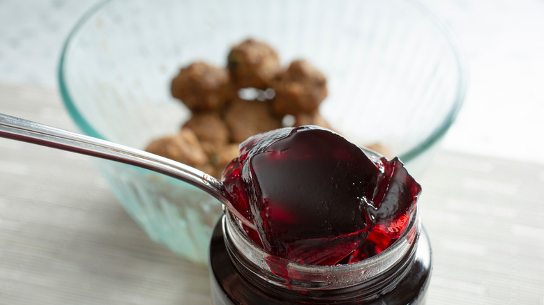 Spoonful of grape jelly with meatballs in the background