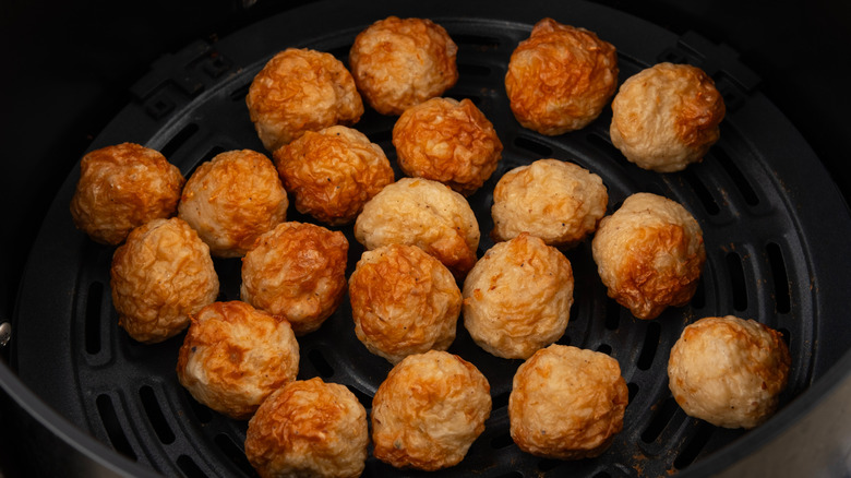 Cooked meatballs in black basket of air fryer