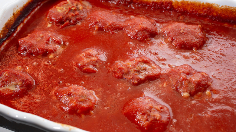 Meatballs covered with marinara sauce on casserole dish