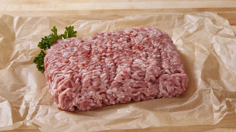 Ground pork on butcher paper with sprig of parsley