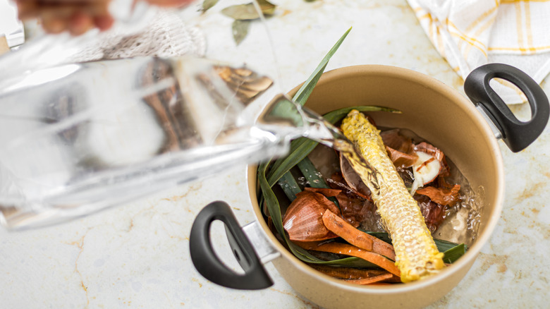 vegetable scraps in a pot being covered with a pitcher of water