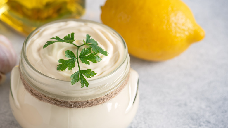 Small glass jar of aioli topped with sprig of parsley