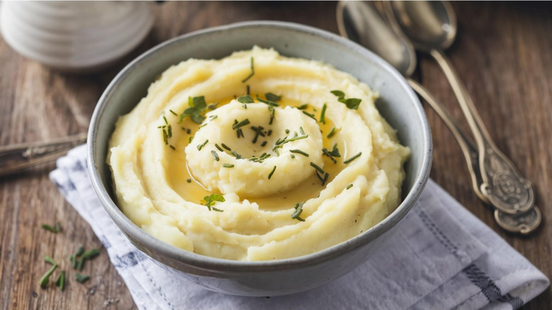 Mashed potatoes in a ceramic bowl topped with chopped chives