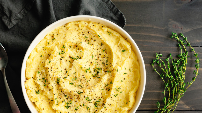 Yukon gold mashed potatoes in a serving bowl topped with thyme leaves