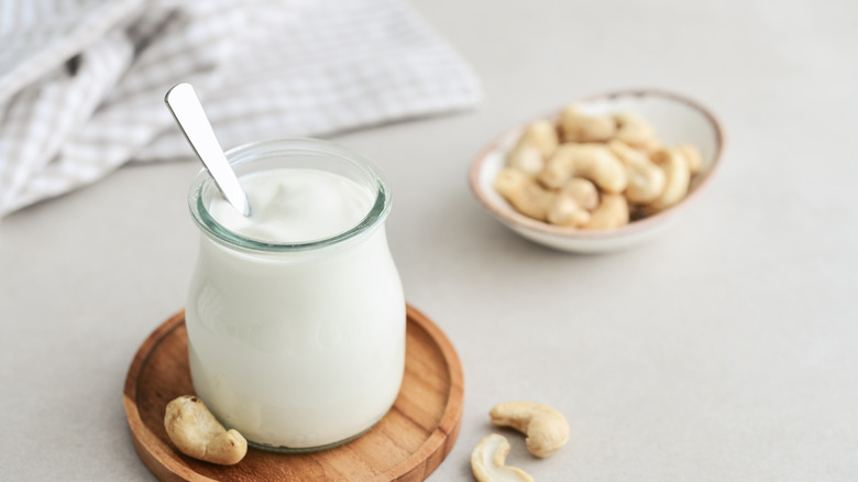 jar of cashew cream with a spoon in it, next to a small bowl of cashews