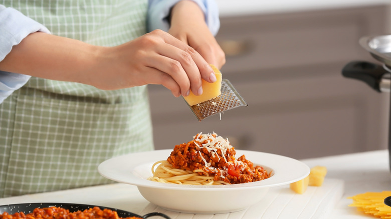 grating cheese over pasta