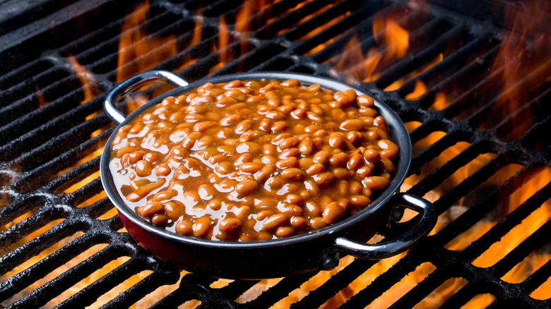 Pot of baked beans on flaming grill grate