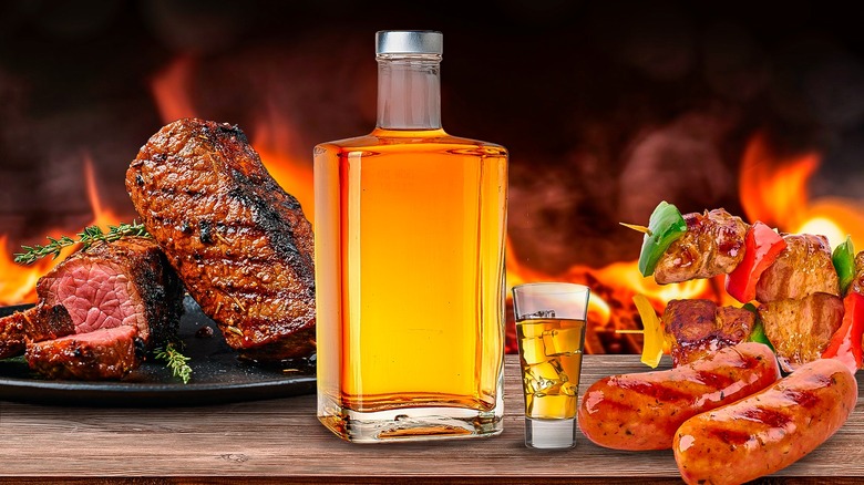 Bottle and glass of bourbon on a table with grilled meats