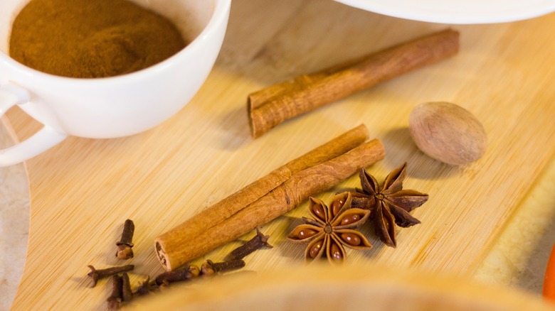 Cinnamon, nutmeg, clove, and anise spices with mug