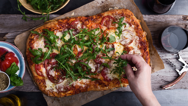 Pizza topped with arugula on parchment paper