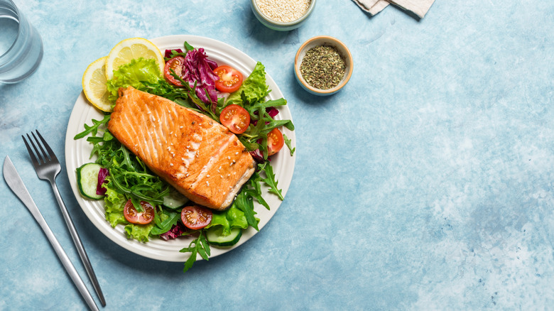 Salmon over arugula with tomatoes and cutlery