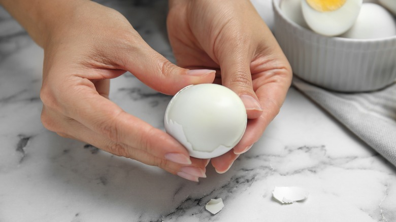 hands peeling an egg