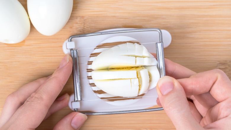 Hands using egg slicer