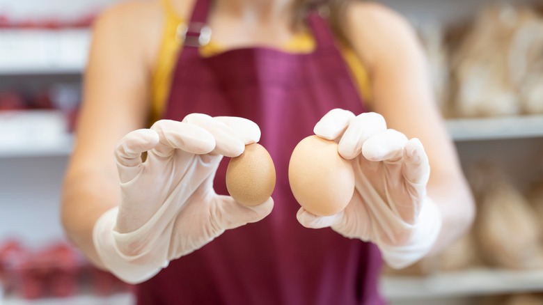 Person holding different size eggs