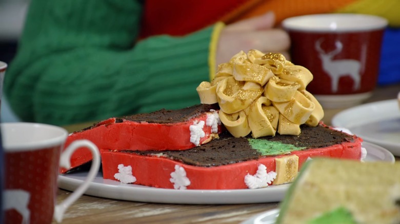 An entire bottle of mulled wine is poured into a cake mix by a contestant on a holiday-themed episode of The Great British Bake Off
