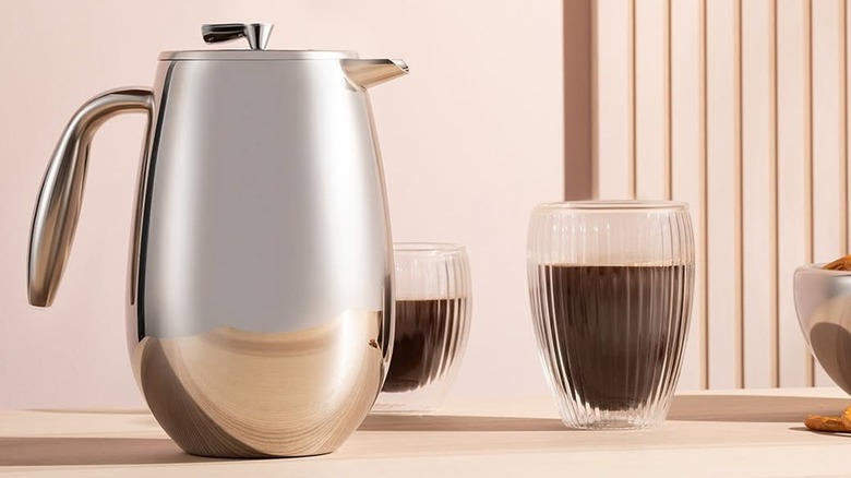 Stainless steel French press in front of two glasses of coffee