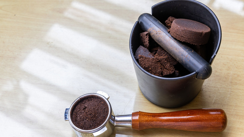 Coffee grounds in knock box next to portafilter