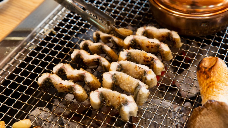 Grilling eel with skewers over charcoal