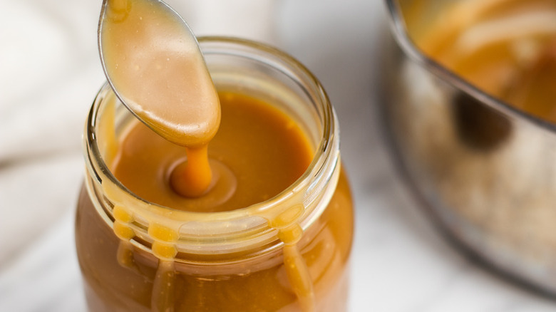 Spooning caramel sauce out of jar