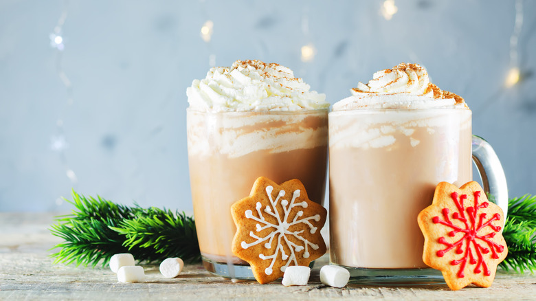 Two gingerbread hot chocolates with whipped cream and cookies