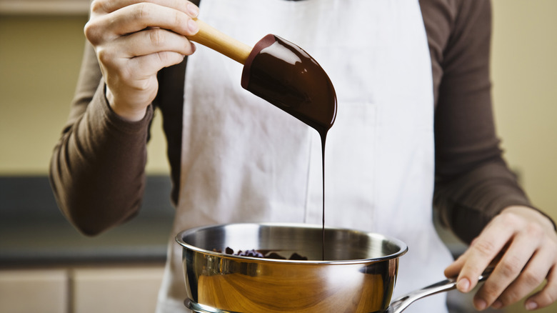 Melted chocolate dripping from spatula into pan