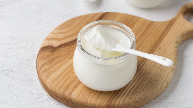 spoon and yogurt in glass jar on wooden board