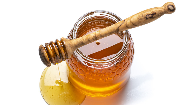 honey dipper on top of jar of honey